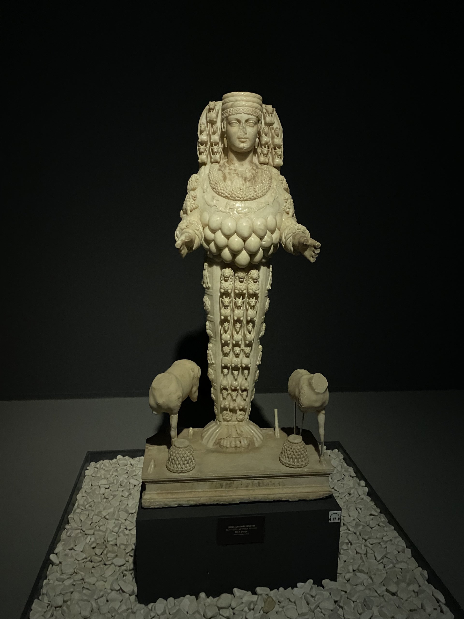 Statue en marbre d'Artémis Éphésienne portant un costume rigide richement orné d'animaux et de protubérances ovoïdes.